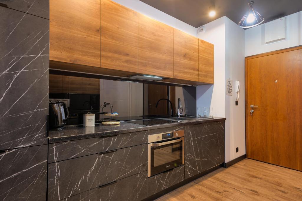 a kitchen with wooden cabinets and a counter top at Wola Luxury Stay in Warsaw