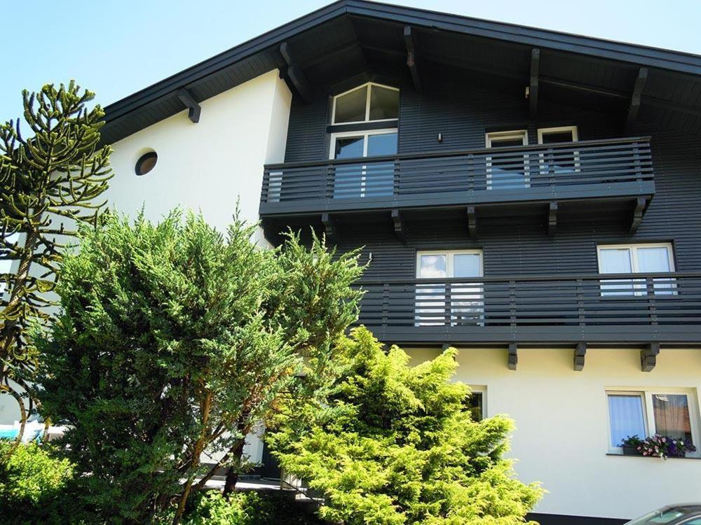 un bâtiment noir et blanc avec des arbres devant lui dans l'établissement Pension Ferienwohnung Pirhofer, à Kramsach