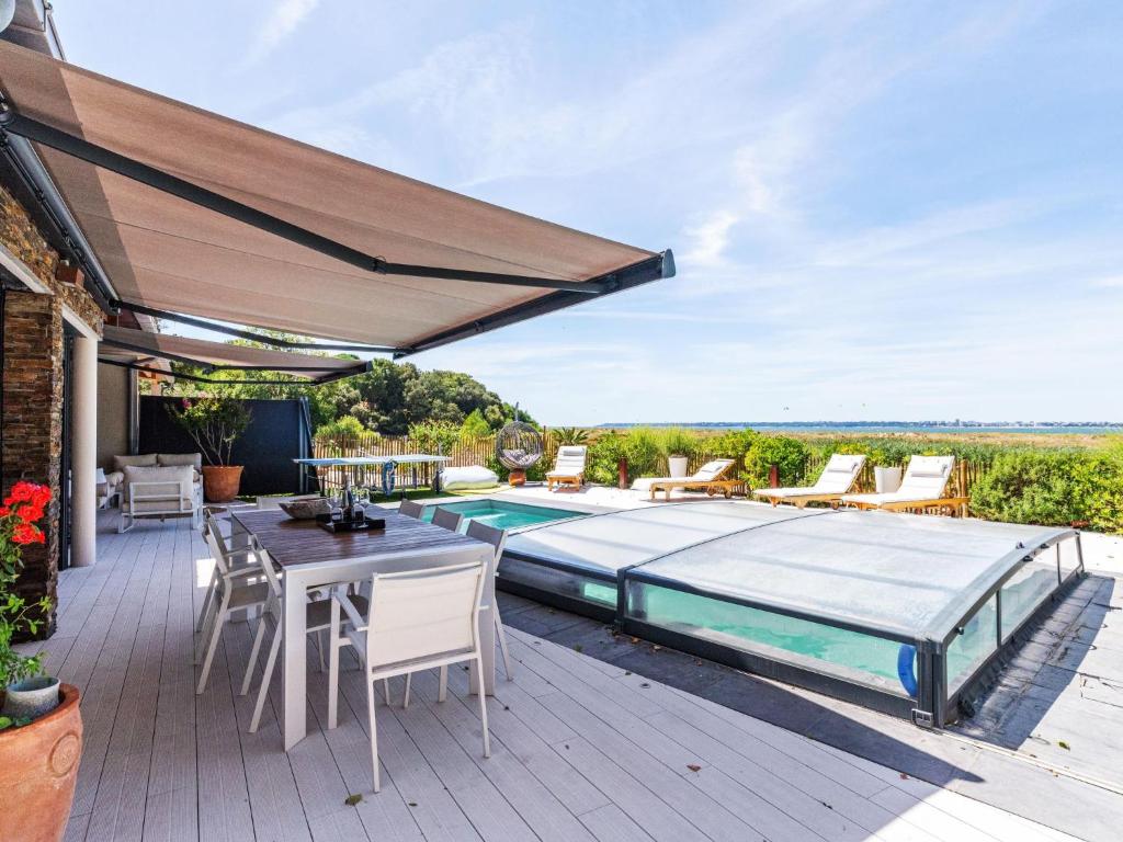 een patio met een zwembad en een tafel en stoelen bij Holiday Home Indigo-Vue Mer et Piscine chauffée by Interhome in Saint-Brevin-les-Pins