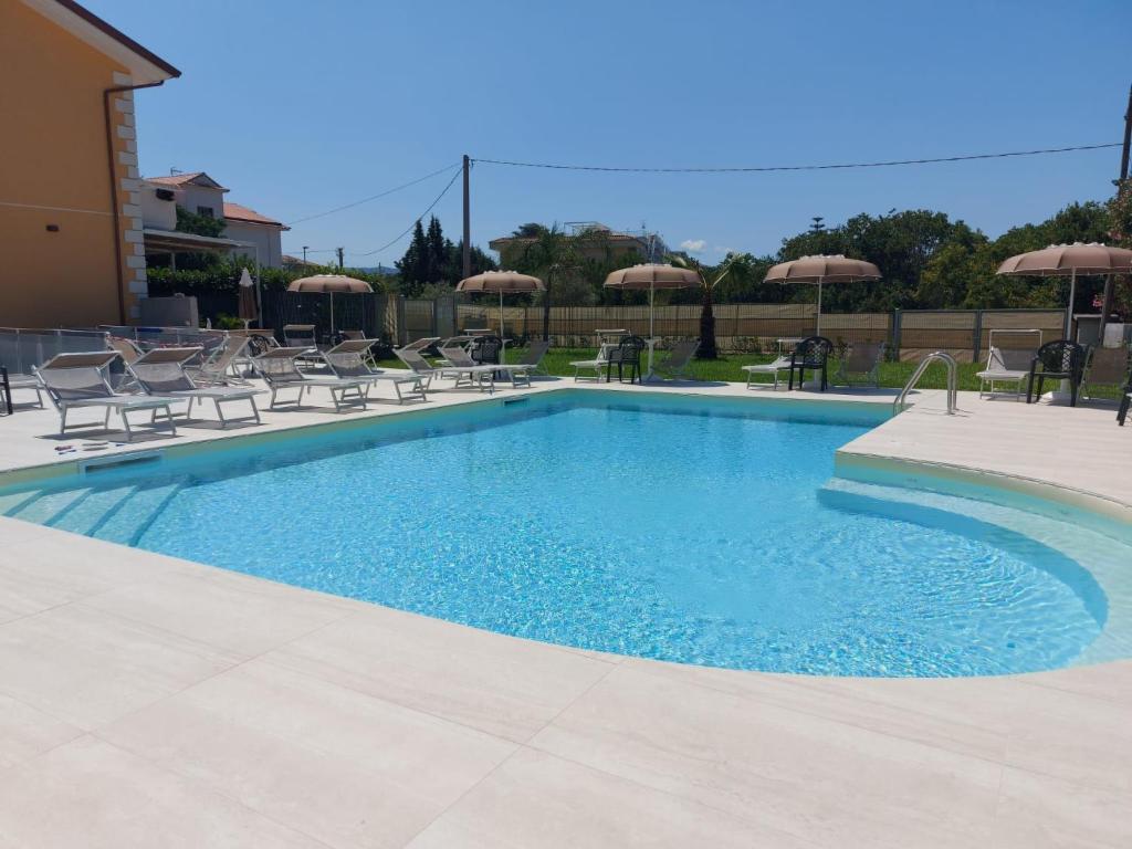 a swimming pool with chairs and umbrellas at Apartment Casale Cilento-1 by Interhome in Paestum