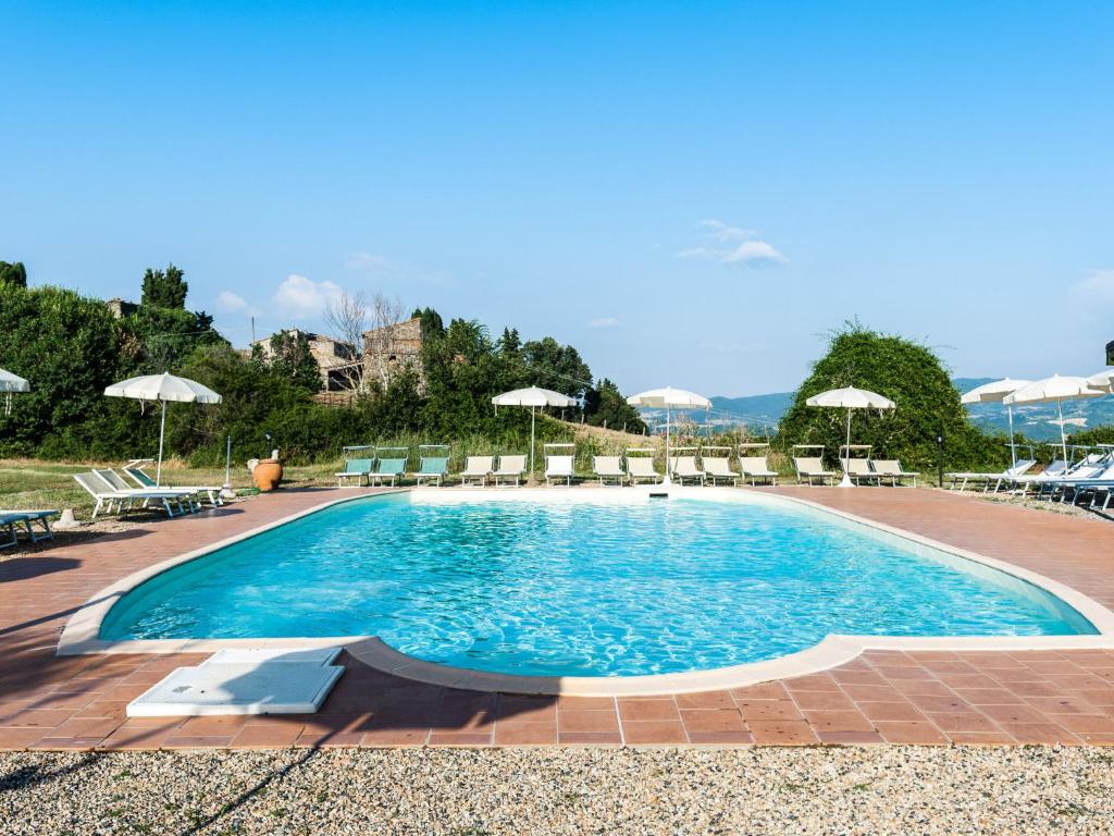 a large swimming pool with chairs and umbrellas at Apartment Borgo Cerbaiola-1 by Interhome in Casa Montacuto