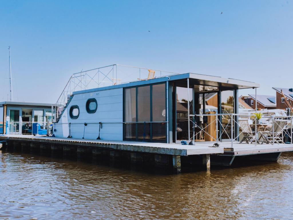 een woonboot geparkeerd bij een dok op het water bij Holiday Home De Meerparel by Interhome in Uitgeest