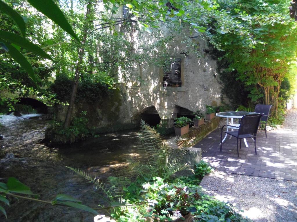 un patio con mesa y sillas en un jardín en À FLEUR D'EAU, en Sainte-Colombe-sur-lʼHers