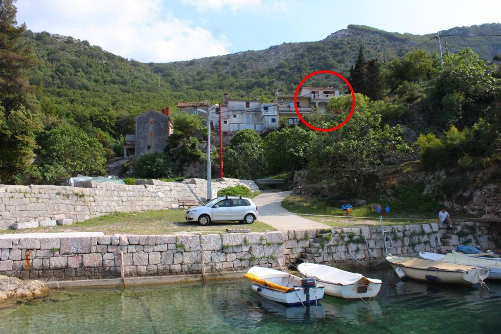 ein Auto, das neben Booten im Wasser parkt in der Unterkunft Apartments by the sea Merag, Cres - 11791 in Cres