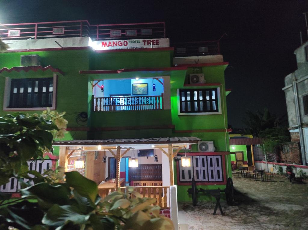 un edificio verde con un cartel en él por la noche en Hotel Mango Tree en Birātnagar