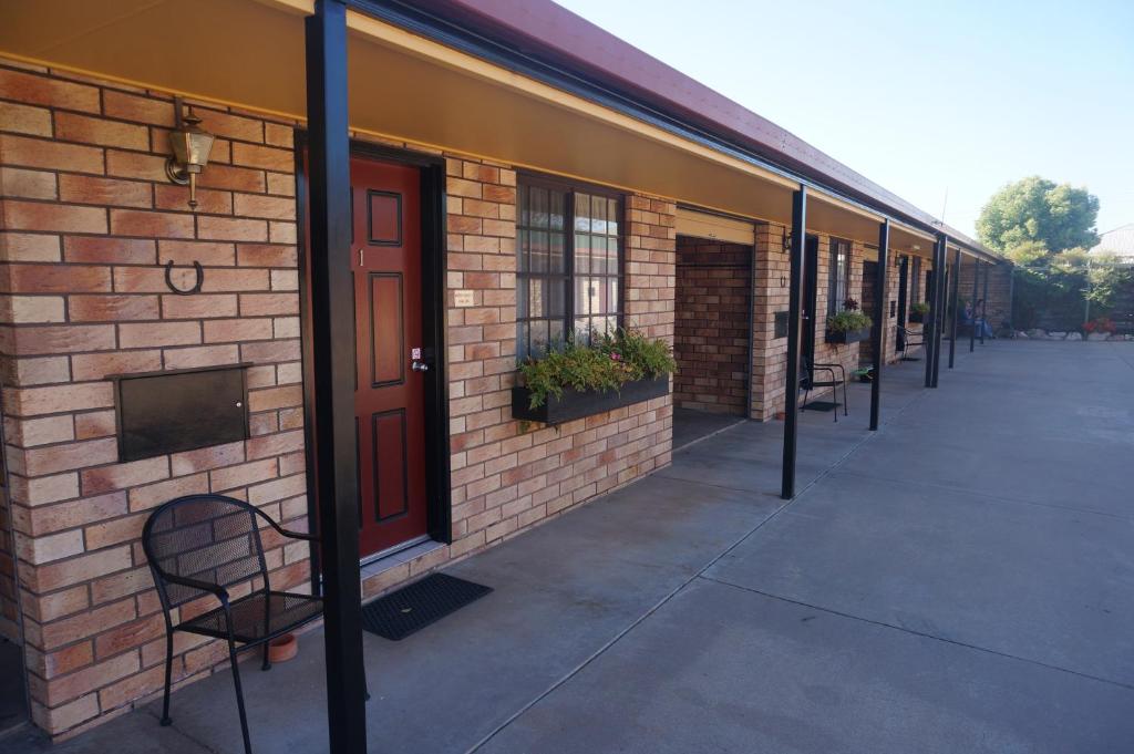 MilesにあるMiles Outback Motelの赤いドアと椅子が備わるレンガ造りの建物