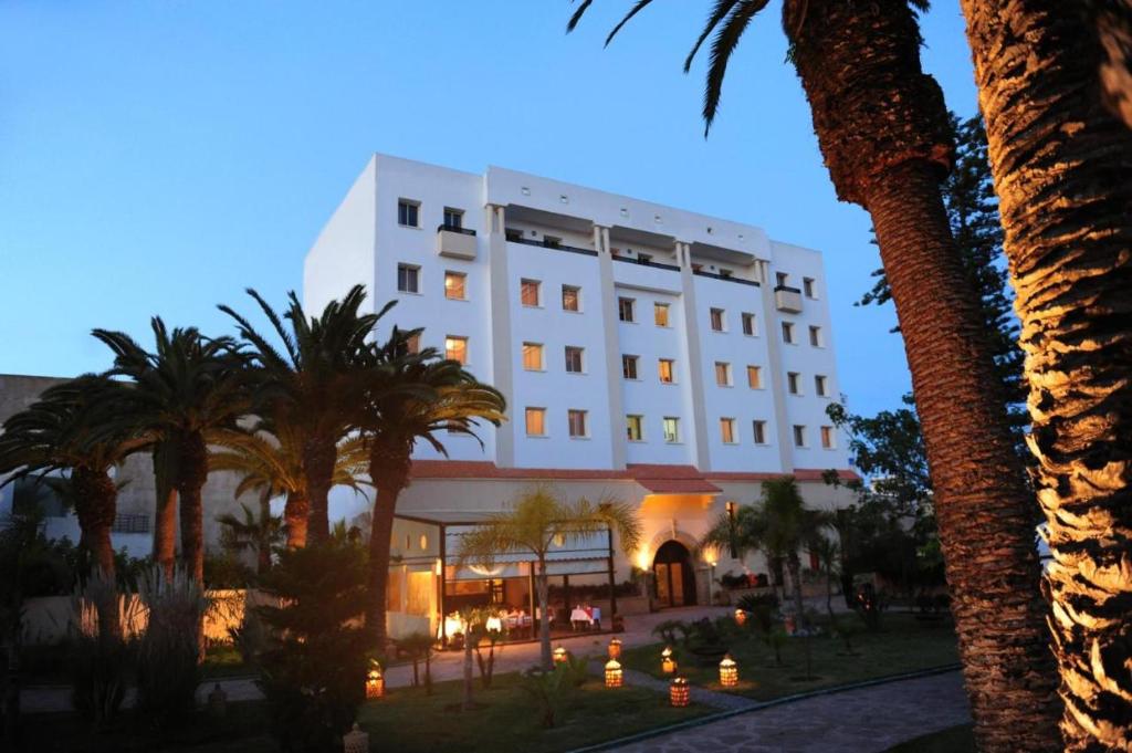 un hôtel avec des palmiers devant un bâtiment dans l'établissement Art suites, à El Jadida