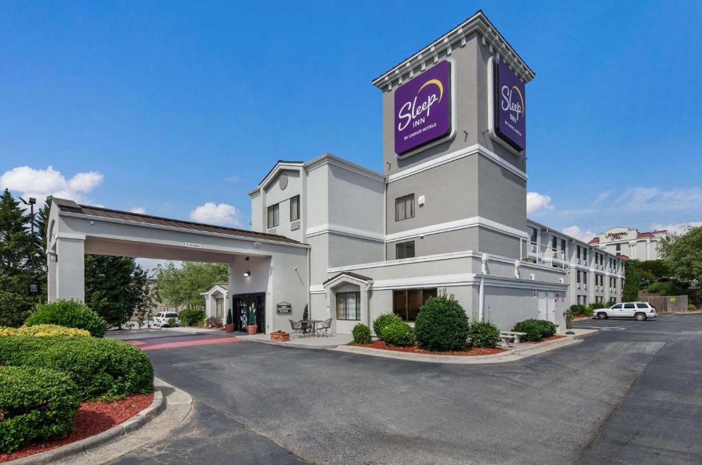 a large white building with a purple sign on it at Sleep Inn Hanes Mall in Winston-Salem