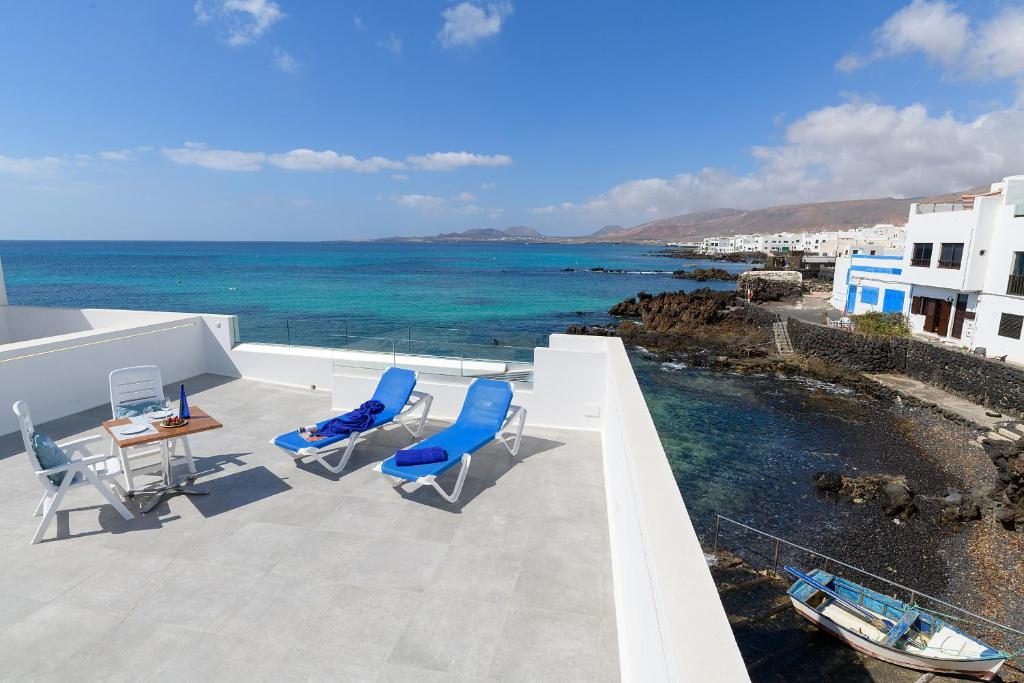 a balcony with blue chairs and the ocean at Casa Berriel in Punta de Mujeres