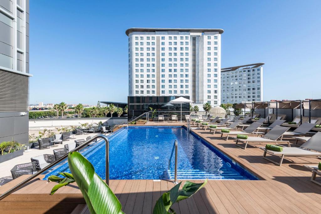 una piscina de hotel con tumbonas y un edificio alto en Melia Valencia, en Valencia