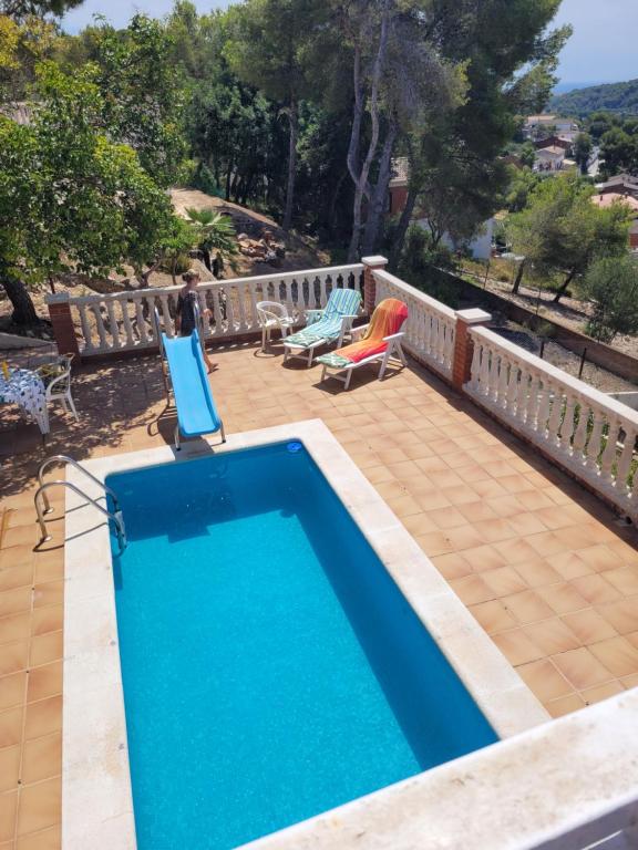 a swimming pool on a patio with two chairs and a table at Cal Jamila in Cubelles