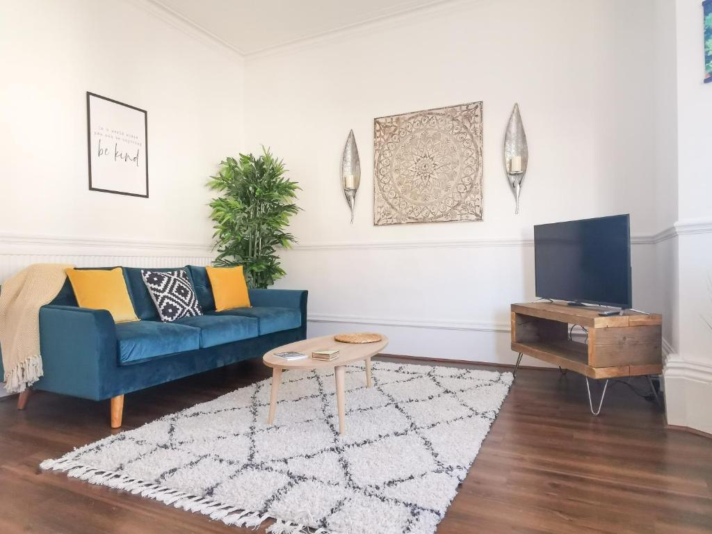ein Wohnzimmer mit einem blauen Sofa und einem TV in der Unterkunft Week2Week 4 BEDROOM BEACH HOME Free Netflix & Wifi in South Shields