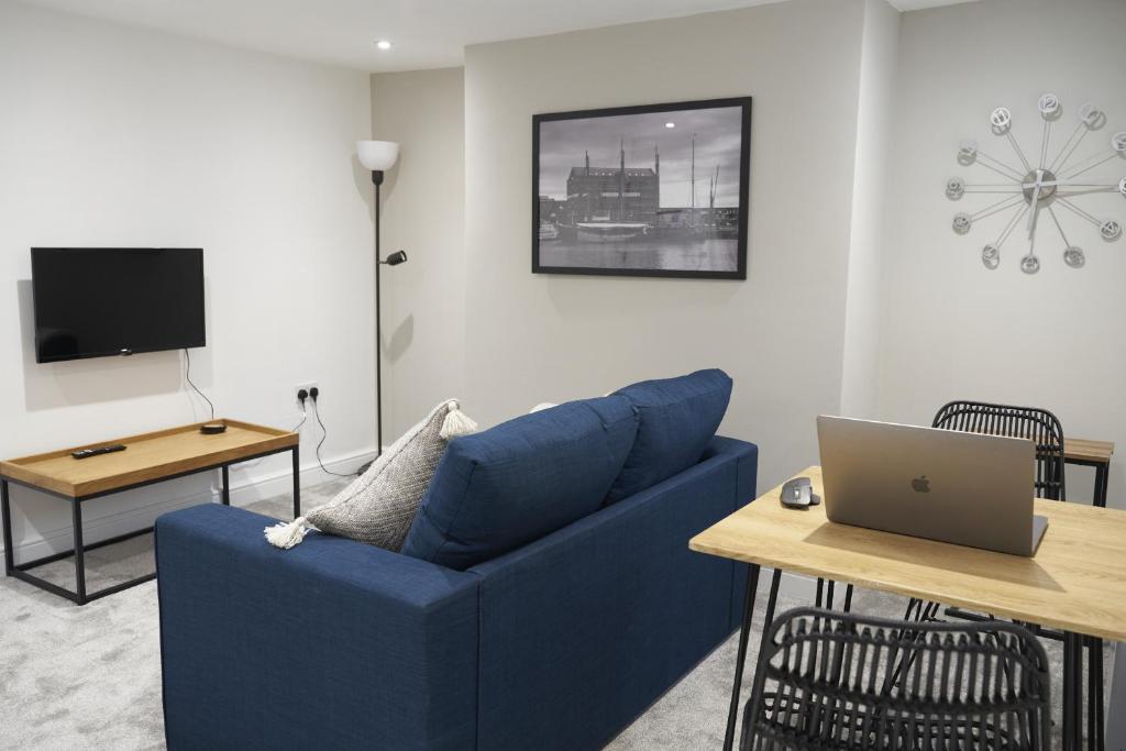 a living room with a blue couch and a table with a laptop at K Suites - Wellington Street 3 in Gloucester