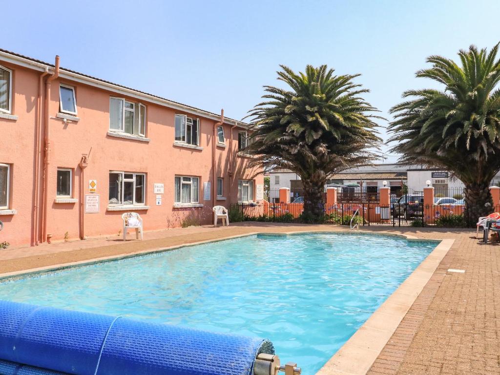 a large swimming pool in a courtyard with palm trees at Flat 18 in Paignton
