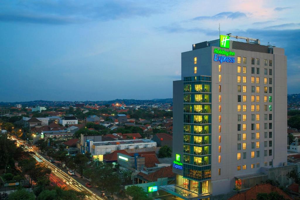 un palazzo alto con un cartello verde sopra di Holiday Inn Express Semarang Simpang Lima, an IHG Hotel a Semarang