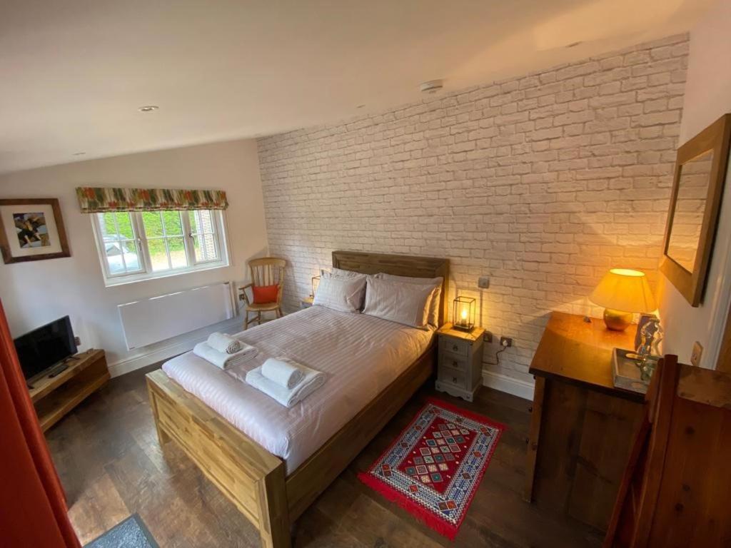 a bedroom with a large bed and a brick wall at Nightjar in Ockley