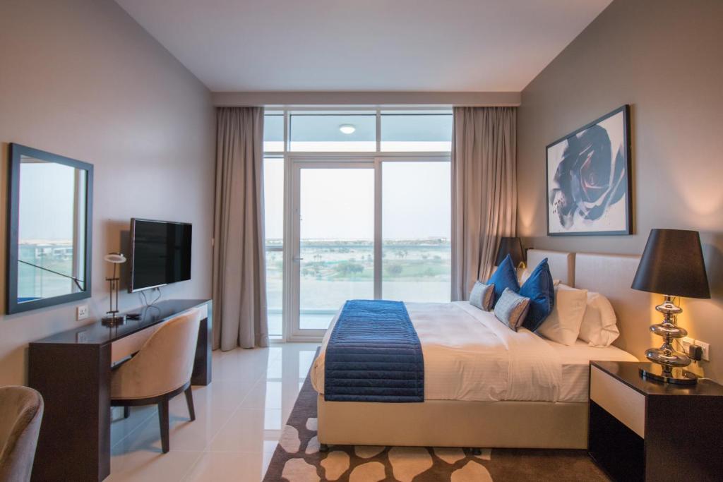 a bedroom with a bed and a desk and a television at Premium Studio with Beautiful Golf Course View in Dubai