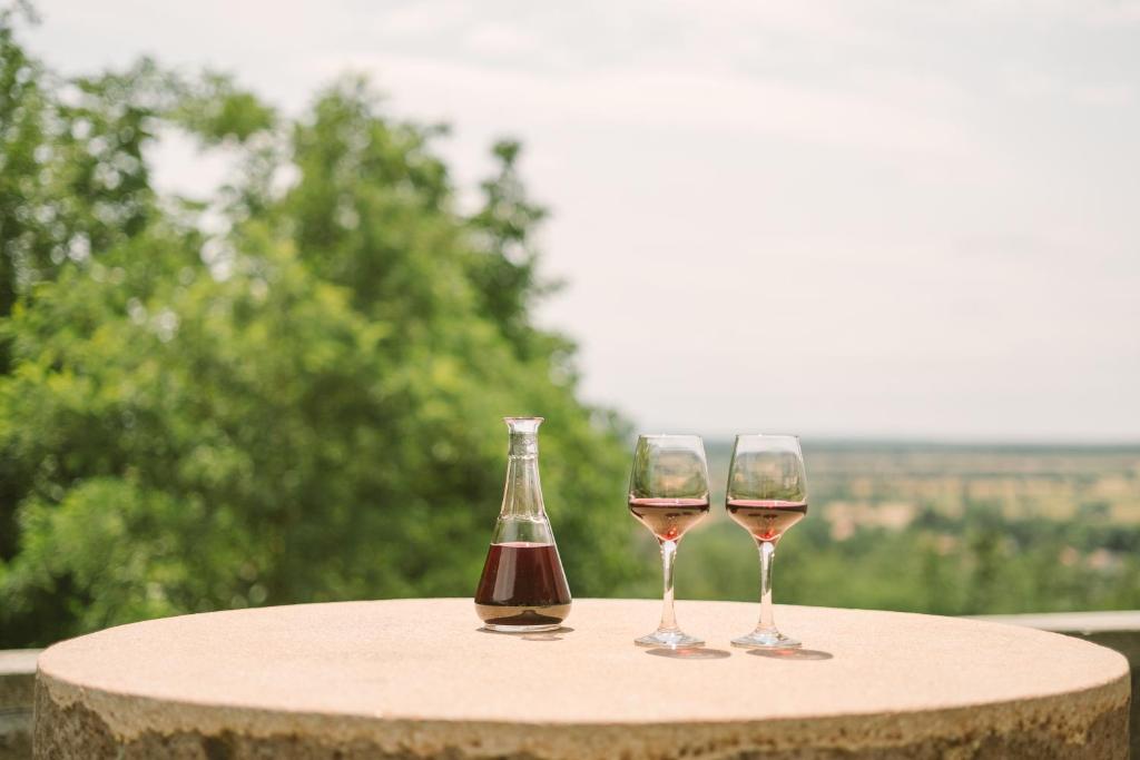 two glasses of wine and a bottle on a table at MacskaFészek Vendégház in Kissomlyó