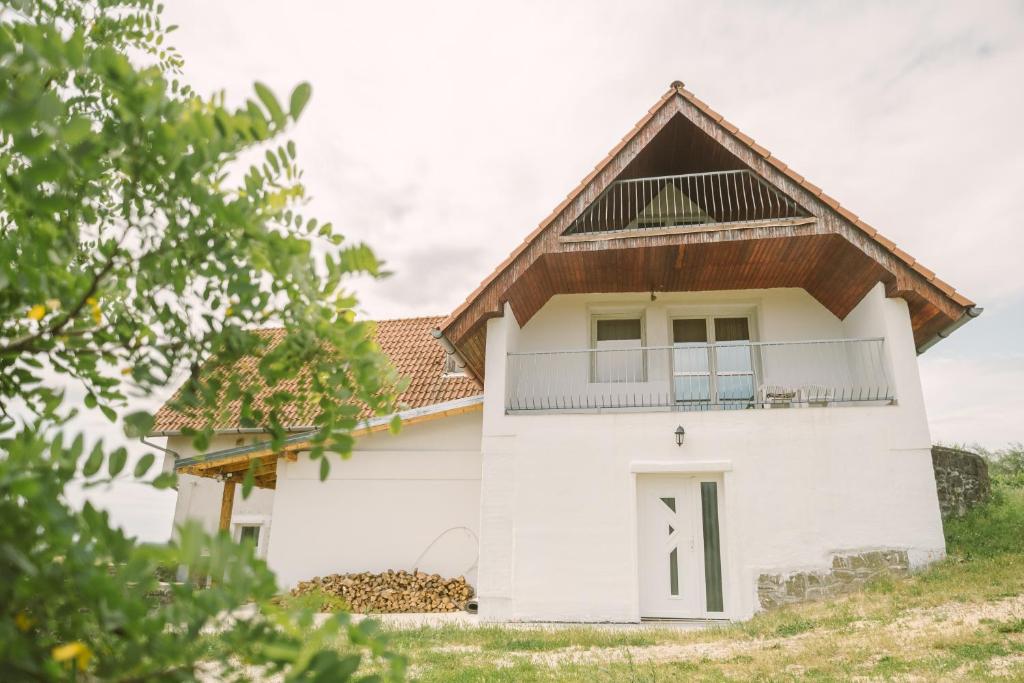 una casa blanca con techo de gambrel en MacskaFészek Vendégház, en Kissomlyó