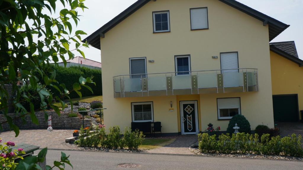 een groot geel huis met een balkon bij Ferienwohnung Hunsrücknest in Malborn