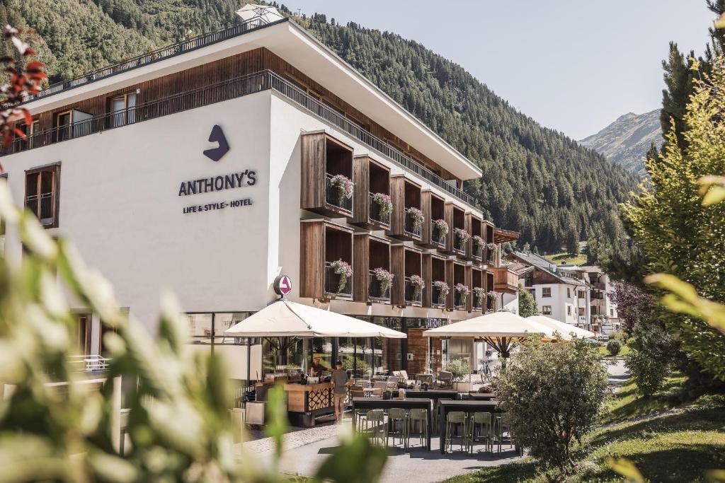 a hotel with tables and umbrellas in front of it at Anthony's Life&Style Hotel in Sankt Anton am Arlberg