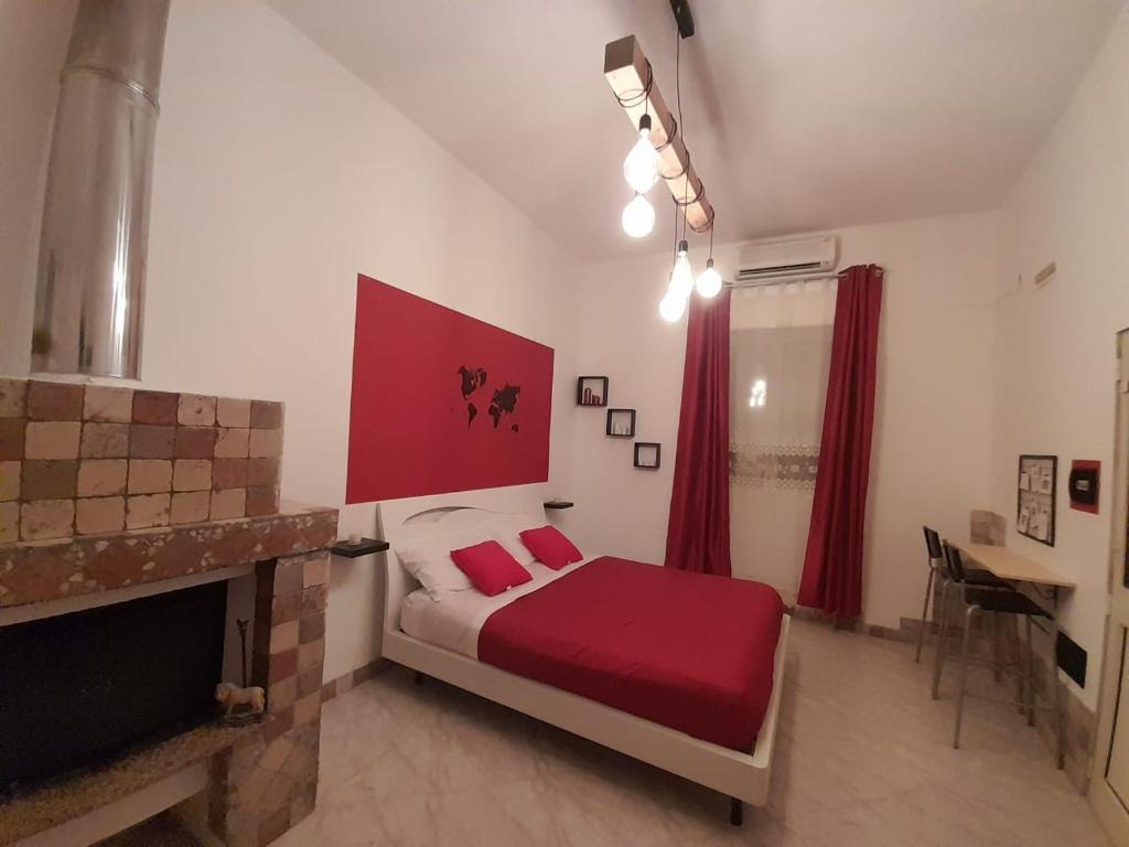 a bedroom with a bed with red sheets and a fireplace at First house in Brindisi