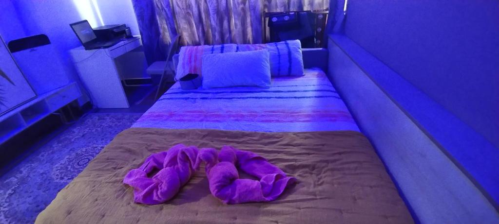 ein Bett mit lila Bettwäsche und Hausschuhen darauf in der Unterkunft CMK TROIKA APARTMEN#Free Netflix in Kota Bharu