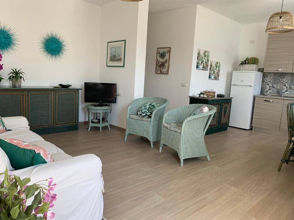 uma sala de estar com um sofá e cadeiras e uma cozinha em Appartamenti a 50 m dal mare da Cecimia's Holiday em Olbia