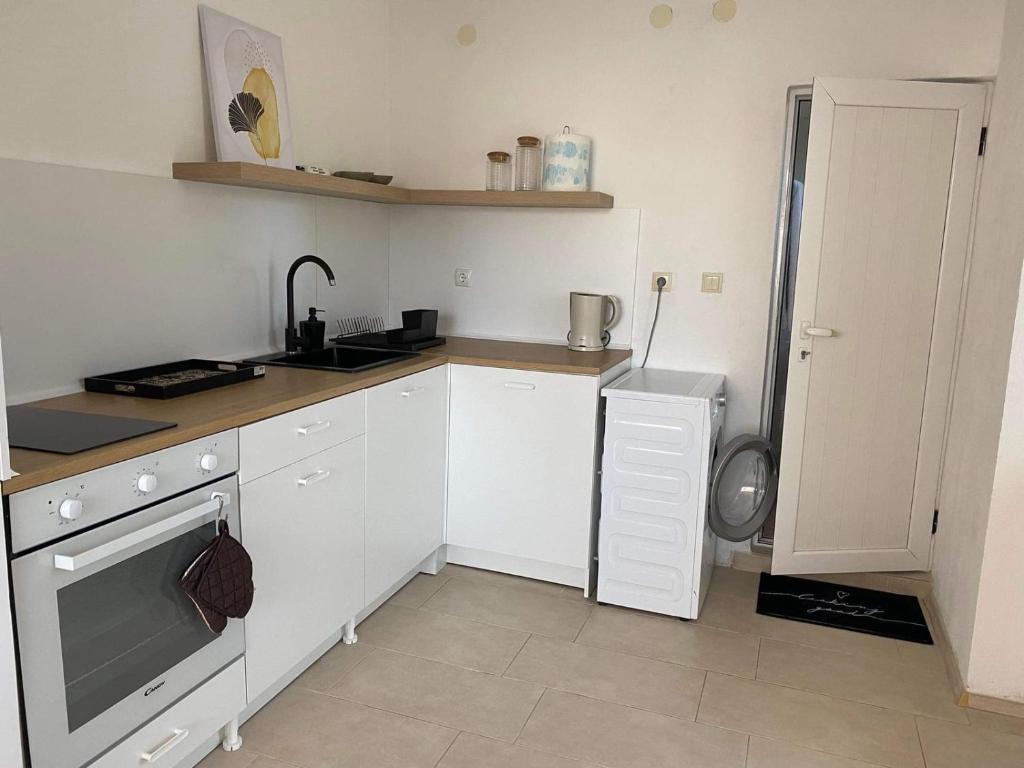 a kitchen with white cabinets and a sink and a dishwasher at Петрови in Chernomorets