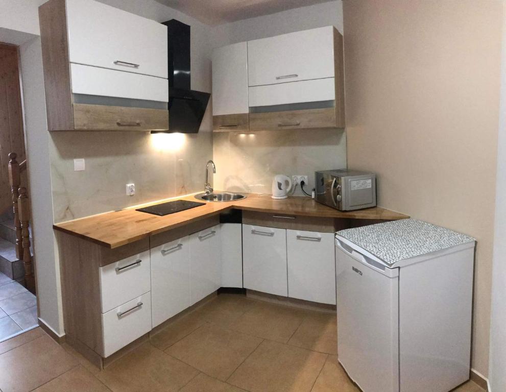 a kitchen with white cabinets and a sink and a refrigerator at U Ani in Poronin