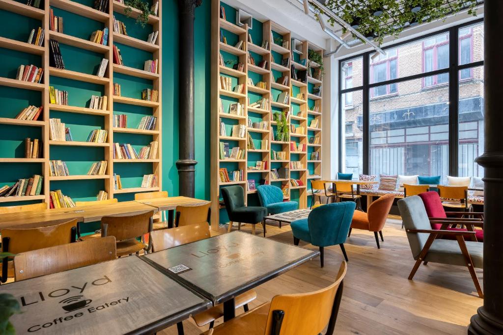 a library with tables and chairs and bookshelves at Aris Grand Place Hotel in Brussels
