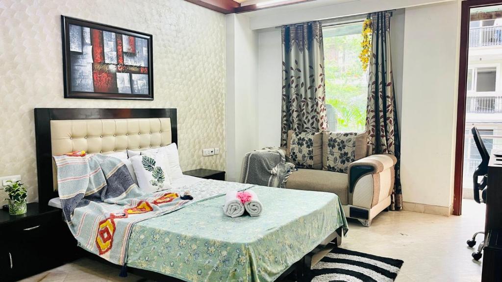 um quarto com uma cama, uma cadeira e uma janela em BluO Cozy Studio with Balcony - Green Park HKV em Nova Deli