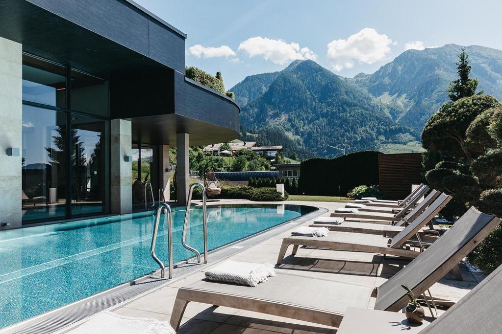 a pool with lounge chairs next to a house at Sonnhof Alpendorf - an adults only place in Sankt Johann im Pongau