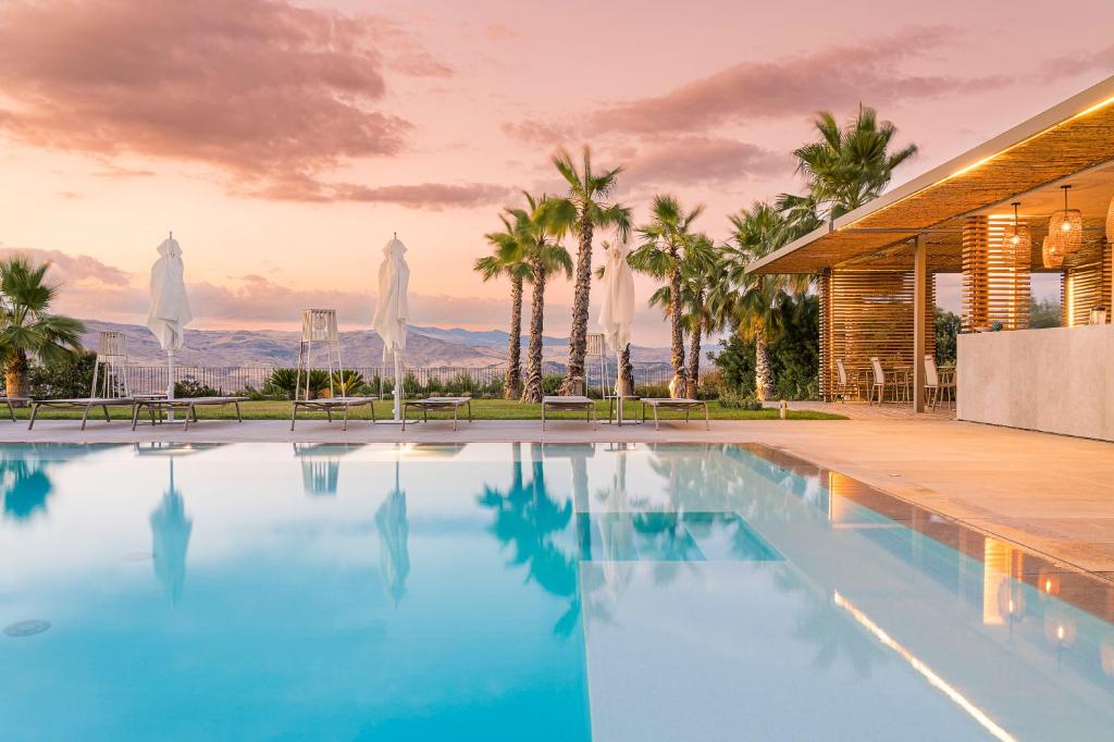 - une piscine en face d'une maison avec des palmiers dans l'établissement Rocca dei Saraceni, à Regalbuto