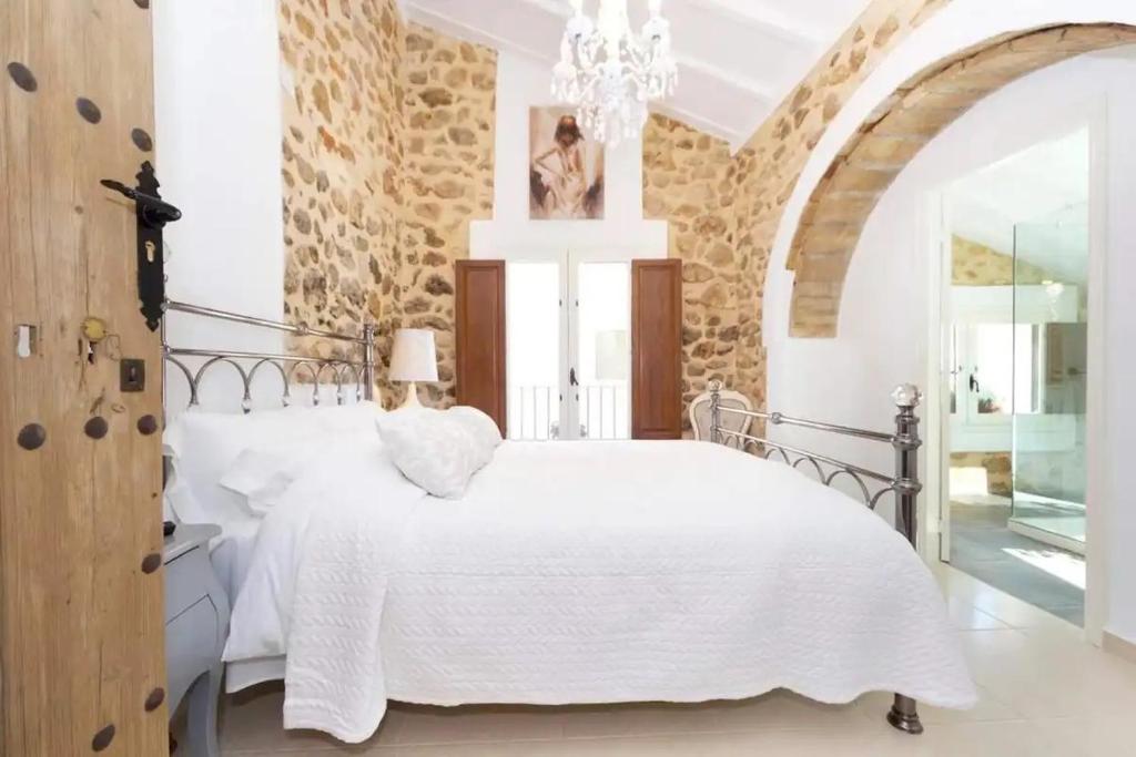 a bedroom with a white bed and a stone wall at Casa Rural Lliber in Lliber