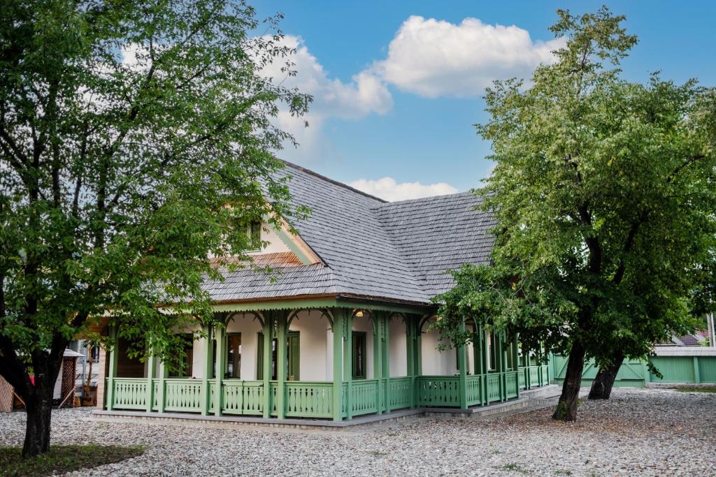 una casa antigua con techo verde y árboles en Dimineți în Cerdac, en Piatra Neamţ