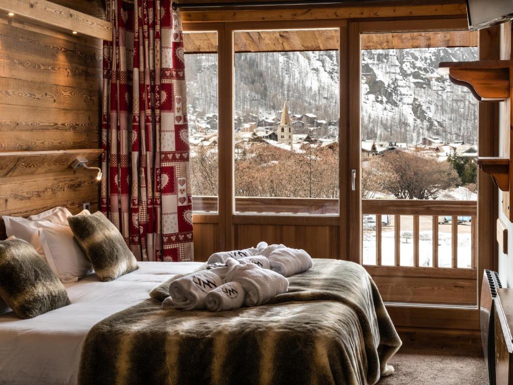 a bed in a room with a large window at Hôtel Ski Lodge - Chambres & Appartements - Village Montana in Val-d'Isère