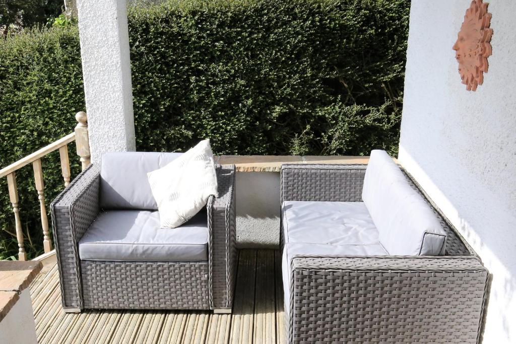 a wicker chair sitting on a porch with two pillows at Edens Horizon cottage annexe in St Austell