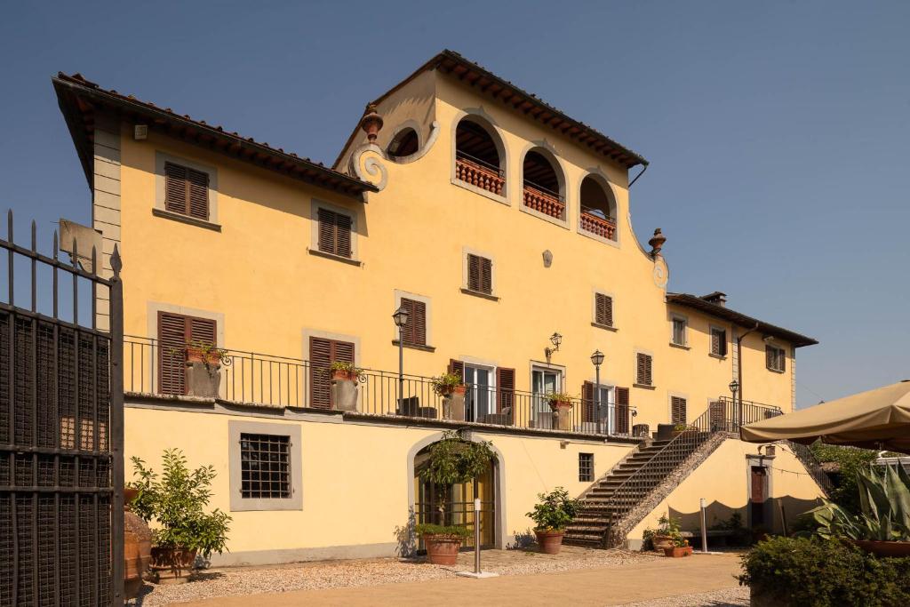 duży żółty budynek ze schodami i oknami w obiekcie Le Farnete w mieście Carmignano