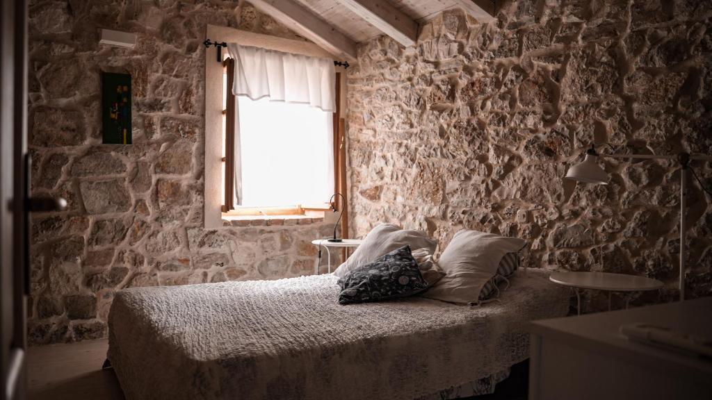a bedroom with a bed and a stone wall at Holiday Homes Susak Sansego in Susak