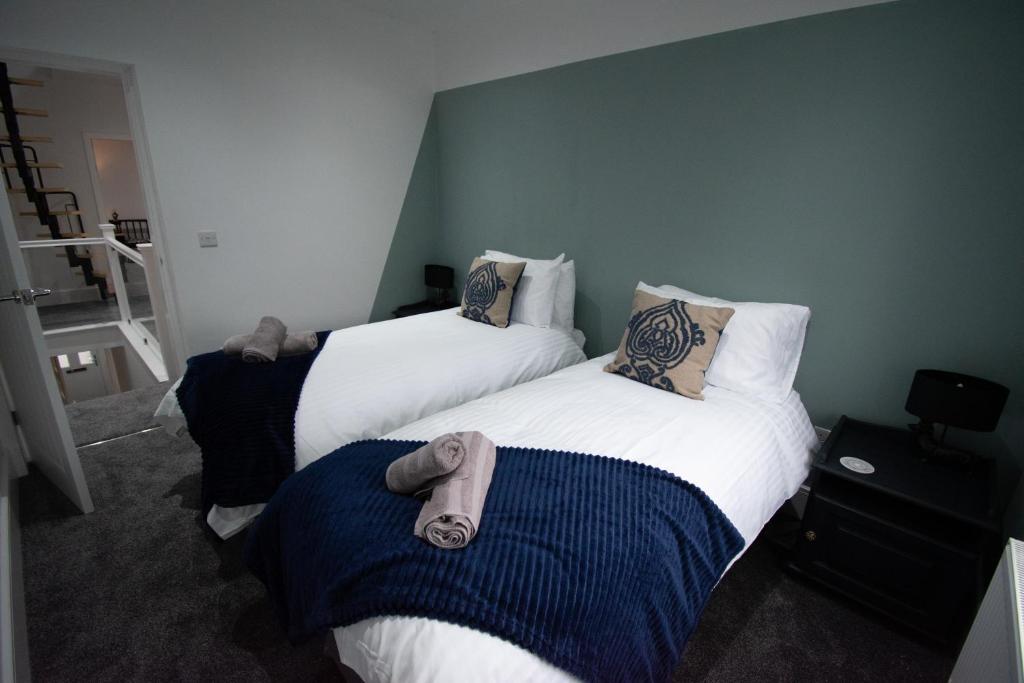 two beds in a hotel room with towels on them at Ideal Lodgings in Accrington in Accrington