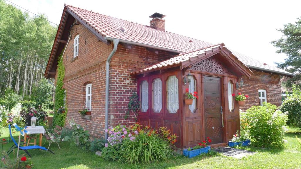 een klein bakstenen huis met een rode deur bij Warmińskie Mieszkanko in Biskupiec