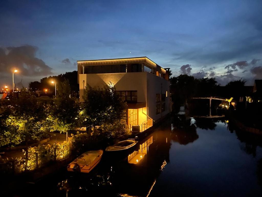 un edificio con un barco en el agua por la noche en Above and Beyond - luxe suite met sauna en stoomdouche en Zaandam