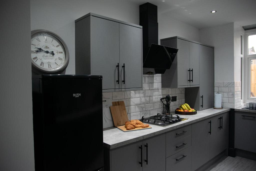 Una cocina con gabinetes blancos y un reloj en la pared. en Ideal Lodgings in Accrington, en Accrington