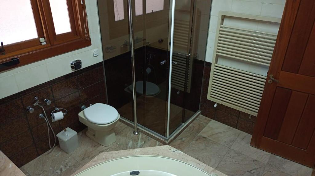 a bathroom with a toilet and a glass shower at Casa Portanova Luxe - A 1,5km da Rua Coberta in Gramado