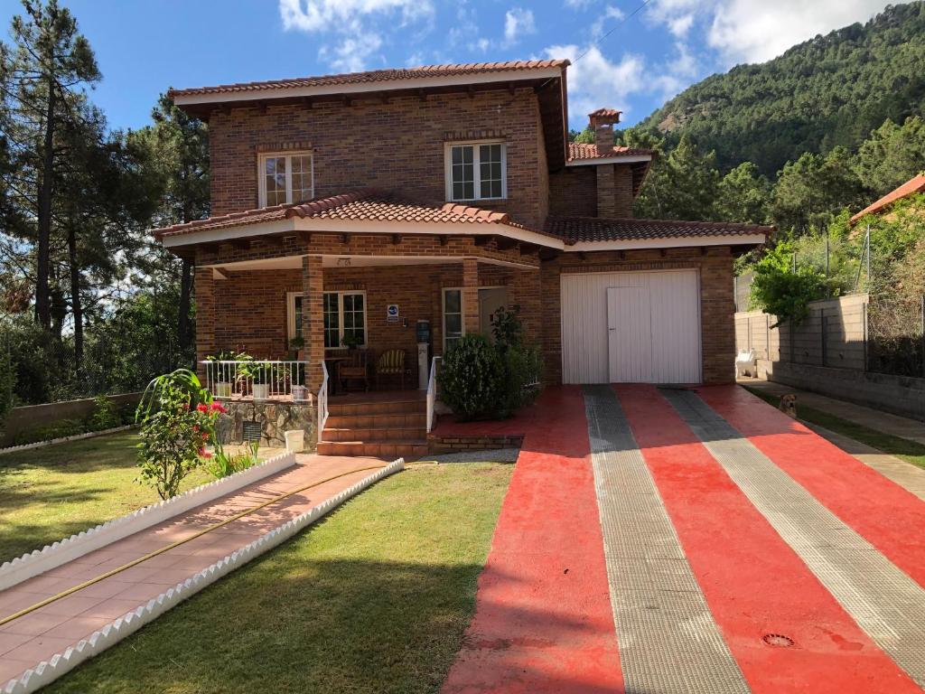 una casa con una alfombra roja delante de ella en CHALET EN EL CORAZÓN DE LA SIERRA DE GREDOS, PINAR DE LA ATALAYA-TIEMBLO, en El Tiemblo