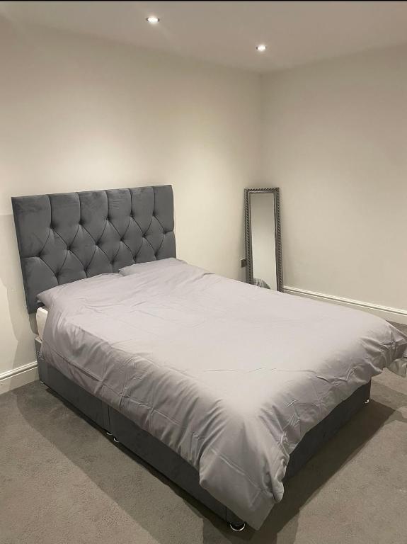 a bedroom with a large bed with a gray headboard at Tee's apartments in Plumstead