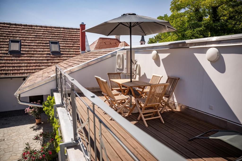 a wooden deck with a table and an umbrella at City-Top Panorama House & Apartments in Esztergom