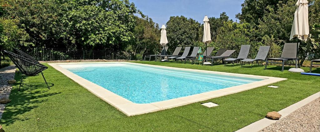a swimming pool with lawn chairs and umbrellas at Gite libecciu in Pietracorbara