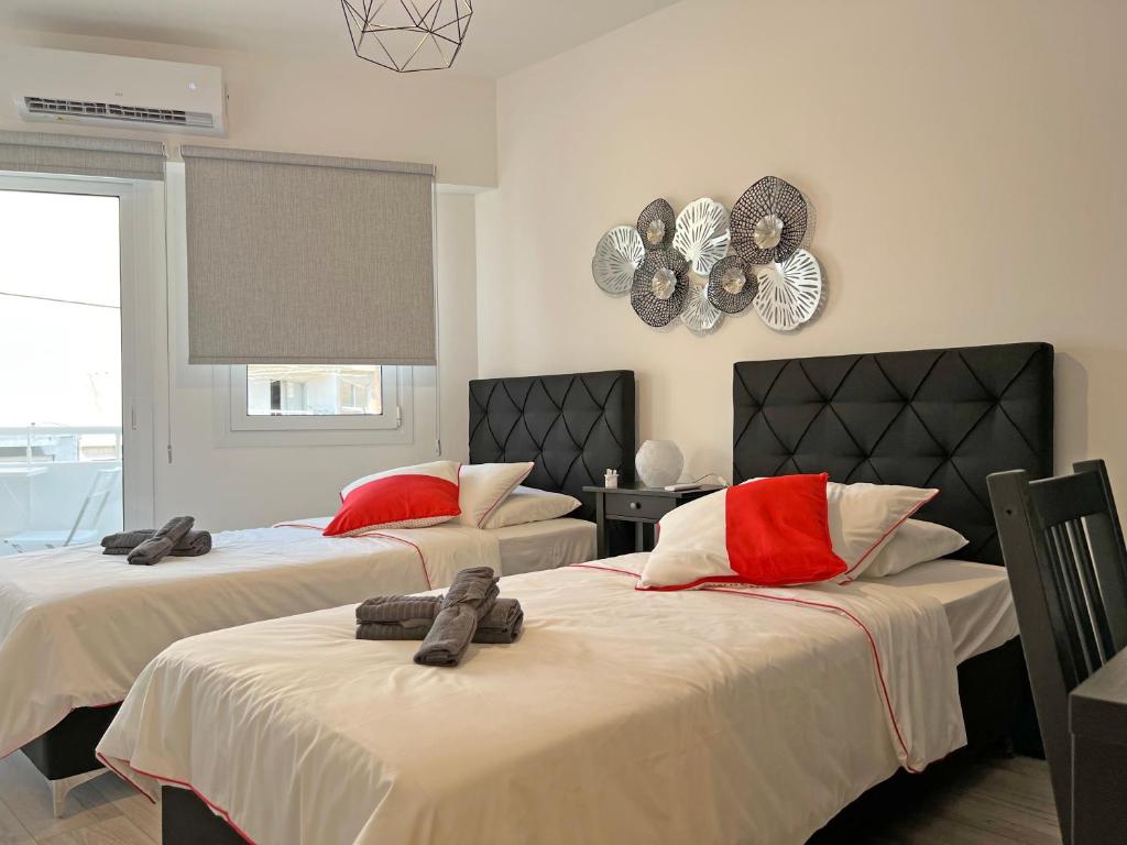 sypialnia z 2 łóżkami i czerwonymi poduszkami w obiekcie Albert's apartment Center 101 w Larnace